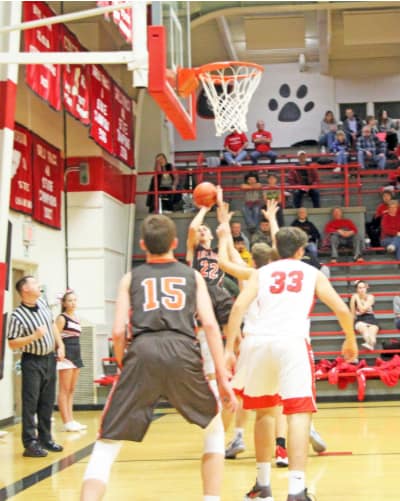 Junior Travis Beetch (far back) takes a shot that is rebounded and banked in for a score by senior Tim Barbieri (15) against Concordia on Friday.